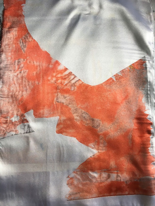 Orange heat transfer print on fabric of leaf silhouettes.