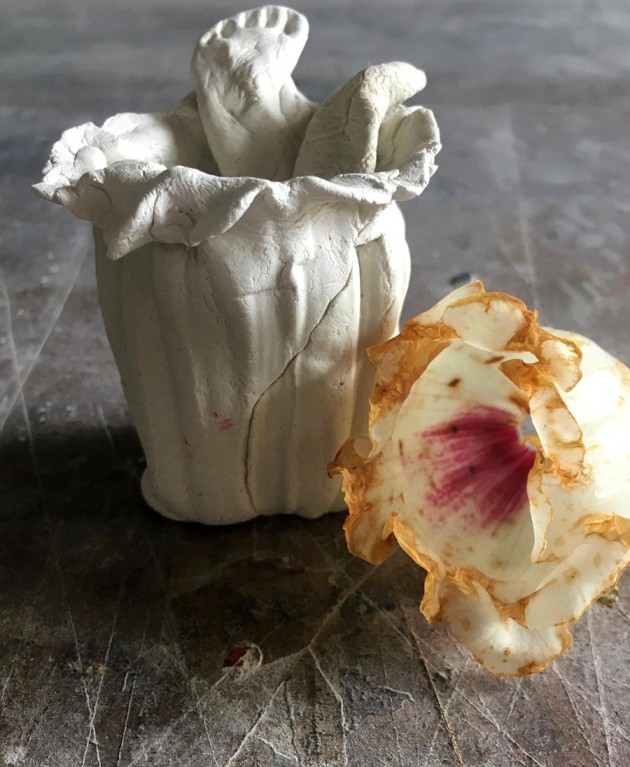 photograph of a ceramic pot with two feet coming out of the top and a rhodendrum flower that inspired it.