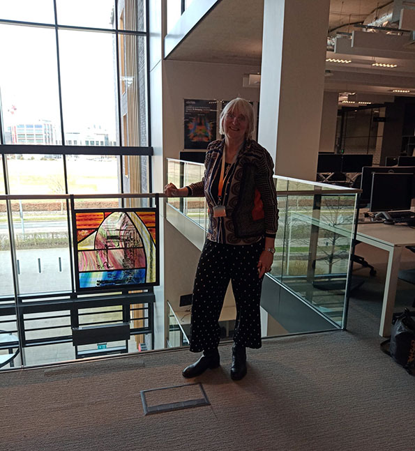 Artist Davina Kirkpatrick with portal panel in situ on glass balustrade at Abcam
