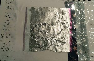 collage of sparkly papers and a impression of a hare on silver paper.