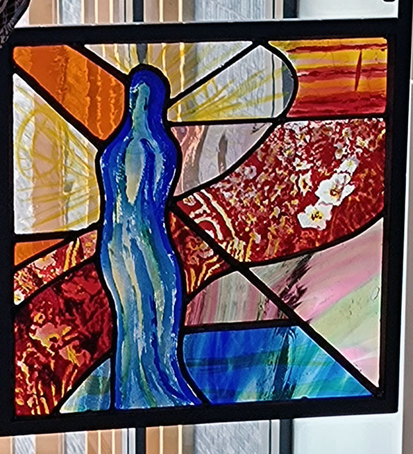 leaded stained glass panel of a etched blue figure and etched red flowers